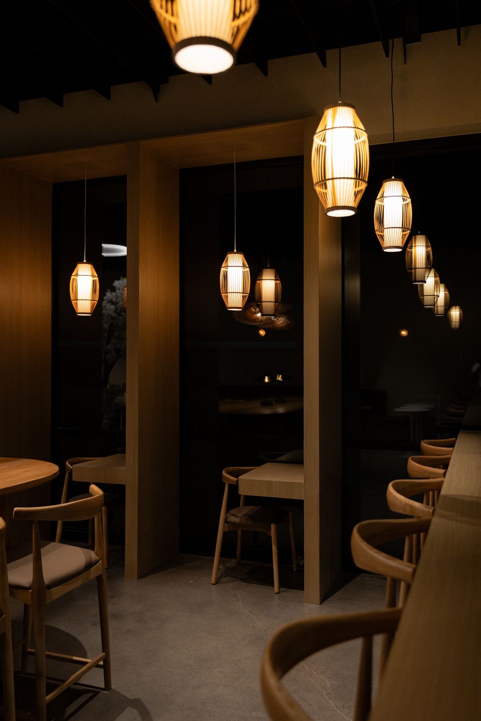 Evening inside Fresso Cafe: oak booths under woven lanterns
